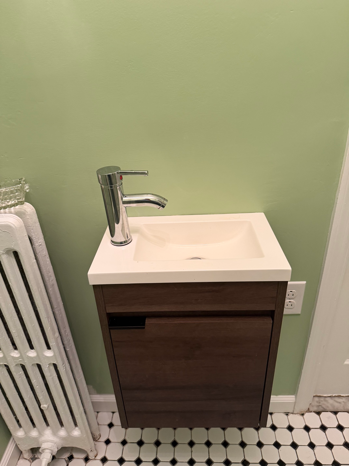 Freshly painted bathroom with soft sage green walls, new white vanity and sink