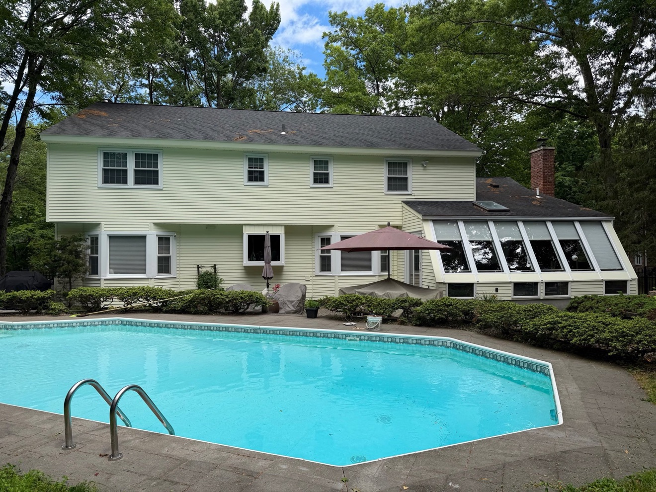 After photo of the Exterior Repaint in Delmar, NY — back of house with swimming pool and fresh yellow siding