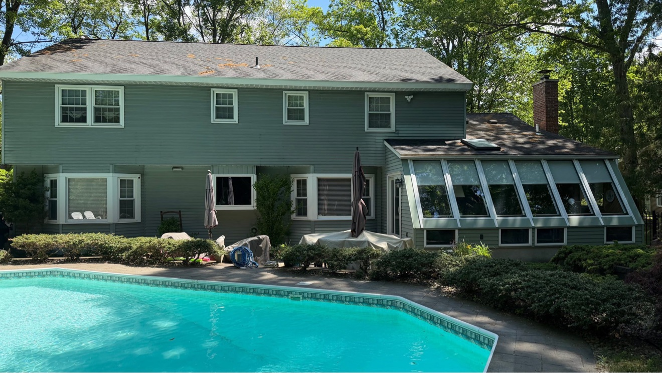 Before photo of the Exterior Repaint in Delmar, NY — back of house with swimming pool and green siding before painting