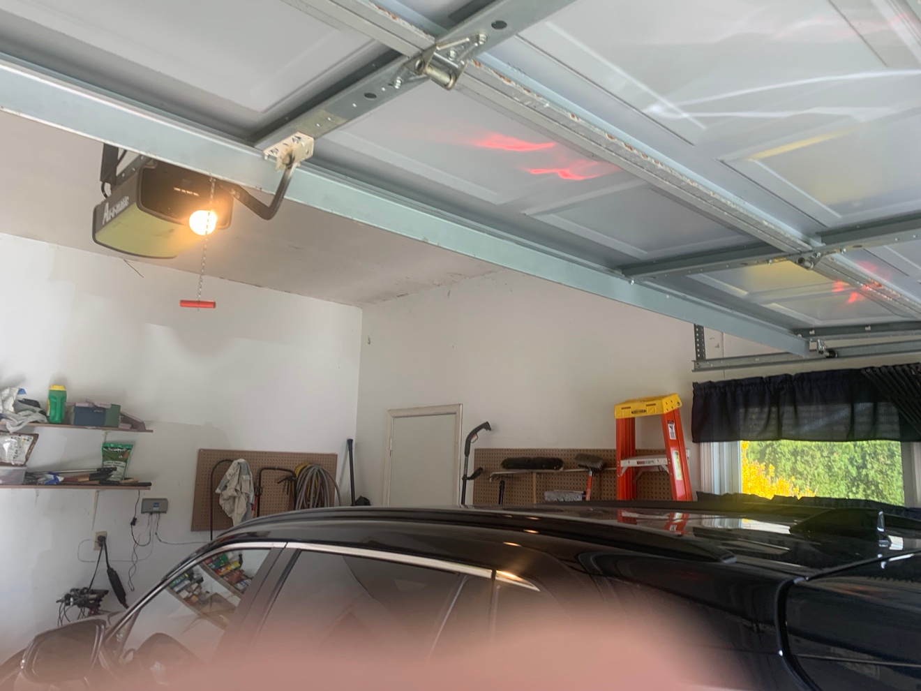 Garage interior before re-taping: garage door tracks, parked car, and walls with old drywall seams visible
