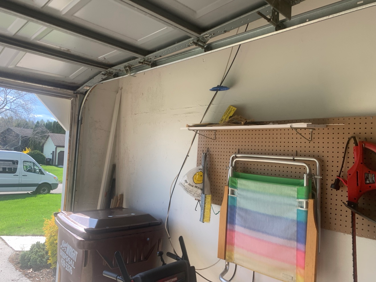 Garage wall near door with pegboard and tools; old drywall tape seams visible on wall and ceiling before re-taping
